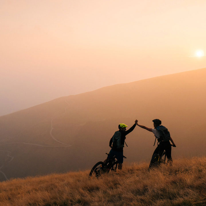 Paar mit Fahrrädern bei Sonnenuntergang auf einem Berg